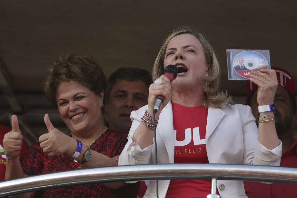 Worker's Party President Senador Gleisi Hoffmann holds up the CD with the registration of Brazil's jailed, former President Luiz Inacio Lula da Silva, as the party's presidential candidate, as former President Dilma Rousseff gives a thumbs up to supporters during a rally in Brasilia, Brazil, Wednesday, Aug. 15 2018. The Workers' Party registered the jailed former president as its candidate for president Wednesday, its latest attempt to muscle him into the race to lead Latin America's largest nation in a showdown with Brazilian electoral authorities. (AP Photo/Eraldo Peres)