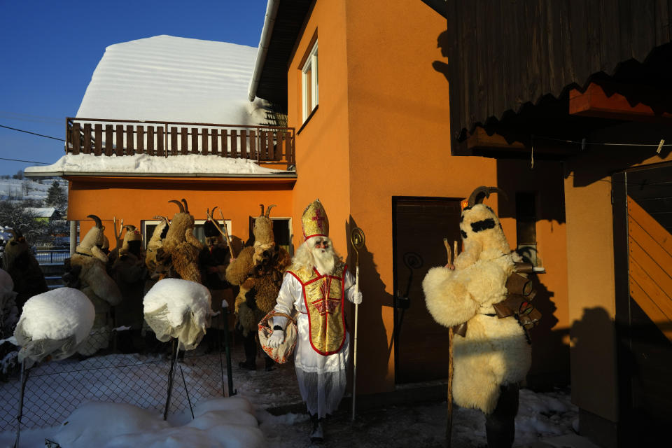 Revelers take part in a traditional St. Nicholas procession in the village of Lidecko, Czech Republic, Monday, Dec. 4, 2023. This pre-Christmas tradition has survived for centuries in a few villages in the eastern part of the country. The whole group parades through the village for the weekend, going from door to door. St. Nicholas presents the kids with sweets. The devils wearing home made masks of sheep skin and the white creatures representing death with scythes frighten them. (AP Photo/Petr David Josek)