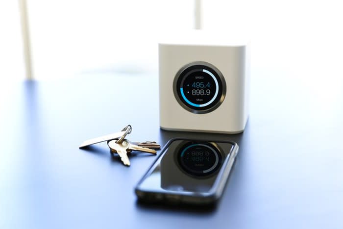 picture of an Amplifi router on a desk with keys and a smartphone.