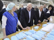 FILE In this file photo taken on Tuesday, April 21, 2020, Belarusian President Alexander Lukashenko talks with an employee during his visit to sewing factory Slavyanka, specializes in producing clothing for adults and children, but recently the production of personal protective equipment has been established to help protect against the coronavirus, in the town of Bobruisk, 150 km (94 miles) southeast of Minsk, Belarus. Last month, Lukashenko abruptly announced that he got the virus himself but had no symptoms and recovered quickly thanks to doing sports. His bravado has angered many in Belarus, and combined with a painful economic fallout from the global pandemic it helped swell the opposition ranks ahead of the vote. (Maxim Guchek/ Pool Photo via AP, File)