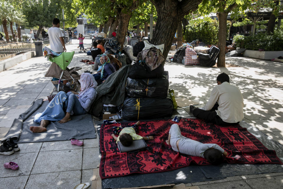 Migrants with their belongings, sit at central Victoria square in Athens, on Wednesday, Sep. 2, 2020. Greece's Shipping Minister says Greek authorities have managed to prevent the arrival of thousands of migrants seeking to enter Greece clandestinely by sea despite a recent lack of cooperation from the Turkish coast guard. (AP Photo/Yorgos Karahalis)