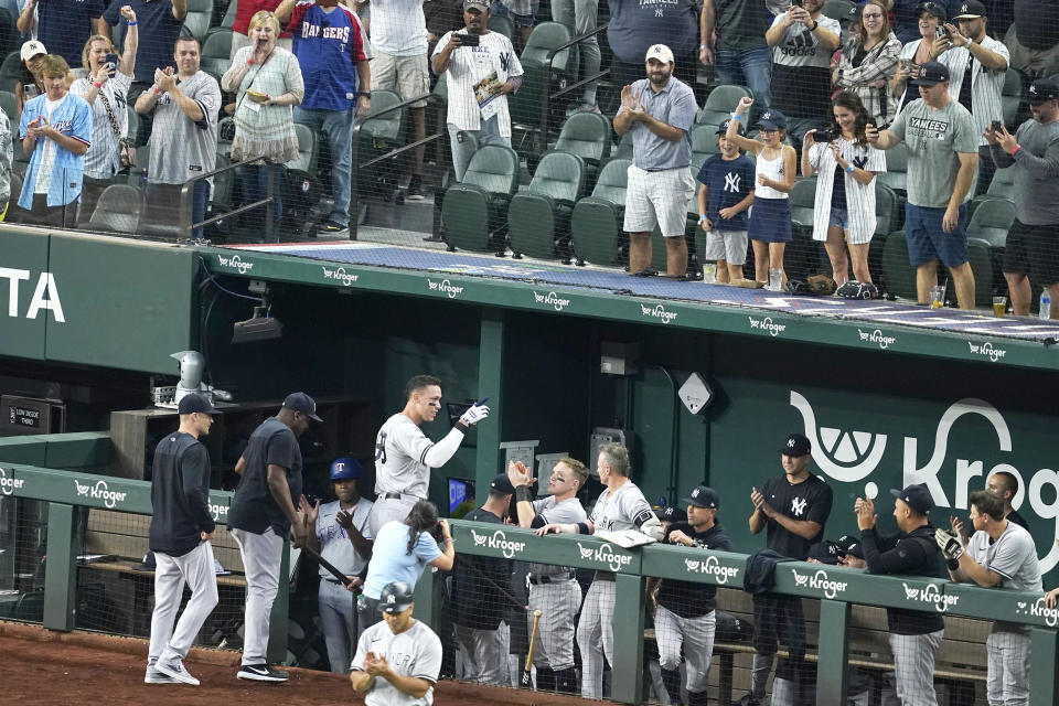 New York Yankees' Aaron Judge, center-left, is greeted at the dugout by teammates and cheering fans after hitting a solo home run, his 62nd of the season, in the first inning of the second baseball game of a doubleheader against the Texas Rangers in Arlington, Texas, on Tuesday, Oct. 4, 2022. With the home run, Judge set the AL record for home runs in a season, passing Roger Maris. (Tony Gutierrez / AP)