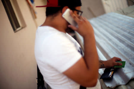 Mexican student Kevin, 20, speaks on his mobile phone while holding a credit card before checking on a money transfer from his mother, who lives in the United States, in Mexico City, Mexico, March 31, 2016. REUTERS/Edgard Garrido