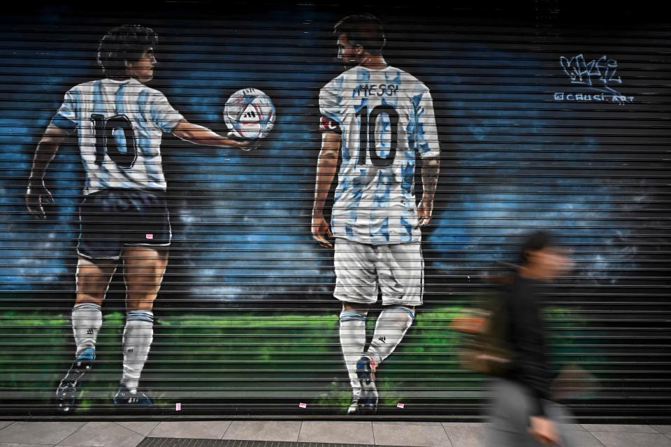 Un mural en Buenos Aires muestra a Maradona pasándole el balón del Mundial a Lionel Messi (Foto: Luis Ropaio/AFP vía Getty Images)