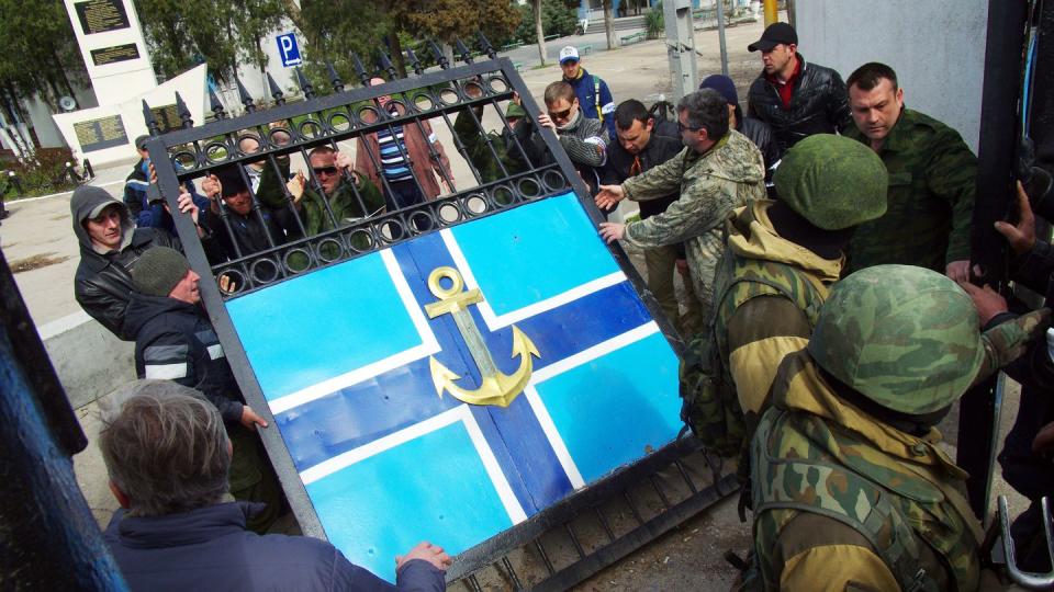 Pro-Russian protesters remove a gate from the Ukrainian Navy headquarters as Russian troops stand guard in the Crimean city of Sevastopol on March 19, 2014. (Vasiliy Batanov/AFP via Getty Images)