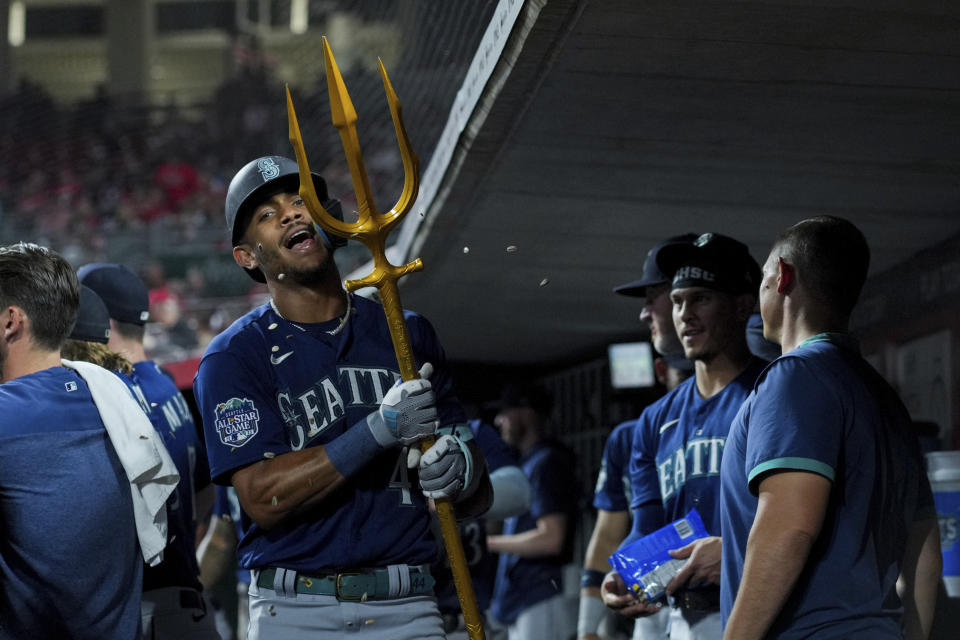 Seattle Mariners' Julio Rodriguez celebrates in the dugout with the trident after hitting a solo home run during the seventh inning of a baseball game against the Cincinnati Reds in Cincinnati, Tuesday, Sept. 5, 2023. (AP Photo/Aaron Doster)