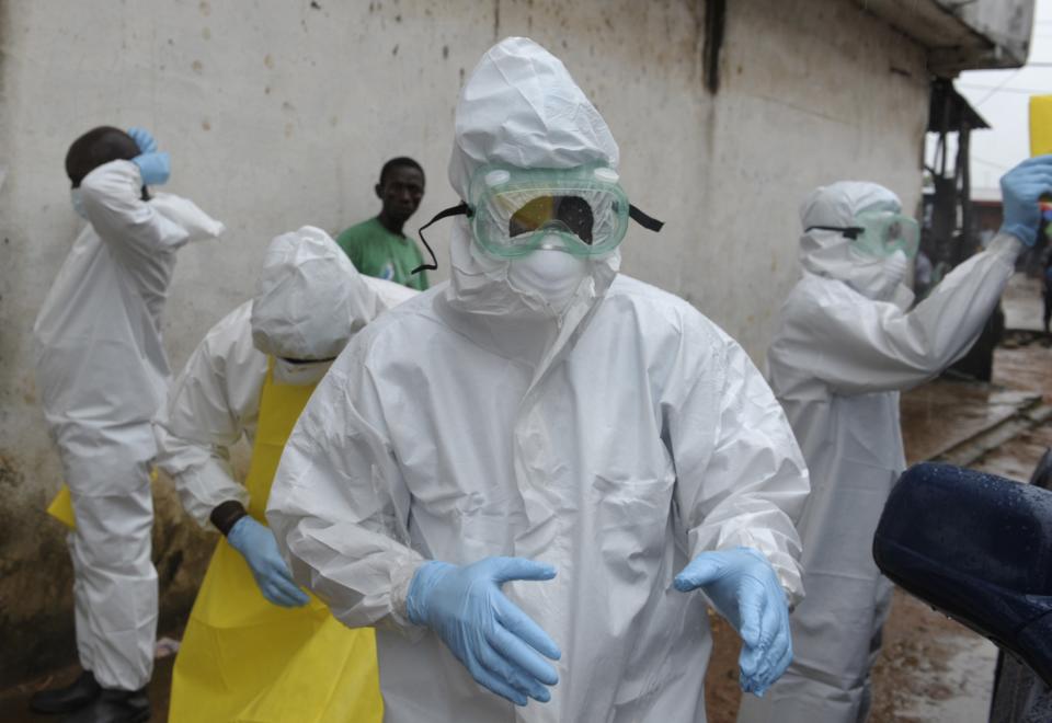 Health workers wearing protective clothing prepare to carry an abandoned dead body presenting with Ebola symptoms at Duwala market in Monrovia August 17, 2014. To try to control the Ebola epidemic spreading through West Africa, Liberia has quarantined remote villages at the epicentre of the virus, evoking the "plague villages" of medieval Europe that were shut off from the outside world. REUTERS/2Tango (LIBERIA - Tags: POLITICS HEALTH DISASTER MILITARY)