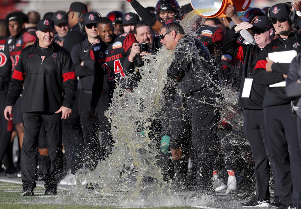 San Diego State assistant coach Brady Hoke is doused as head coach Rocky Long, left, looks on at the end of the New Mexico Bowl NCAA college football game against Central Michigan on Saturday, Dec. 21, 2019 in Albuquerque, N.M. San Diego State won 48-11. (AP Photo/Andres Leighton)