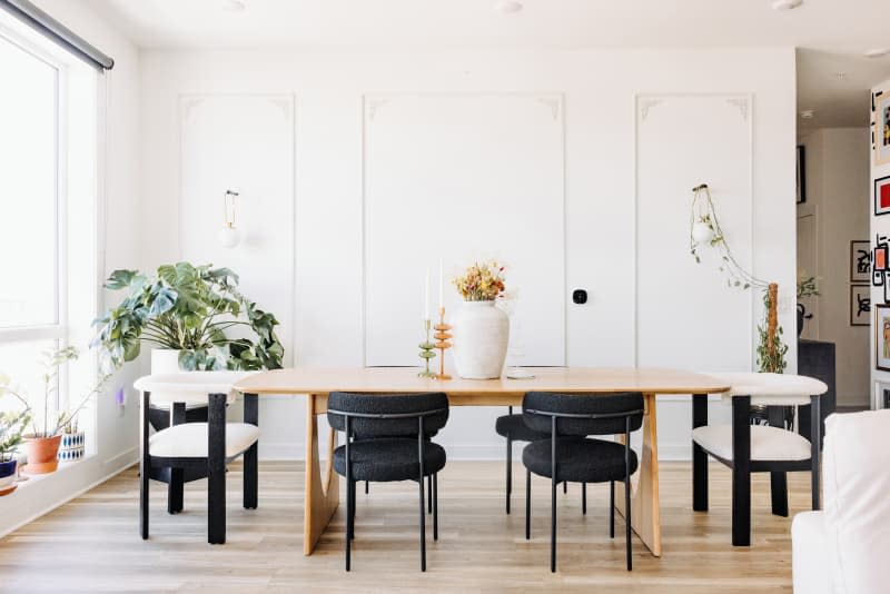 White dining room with large light wood dining table and white and black dining chairs