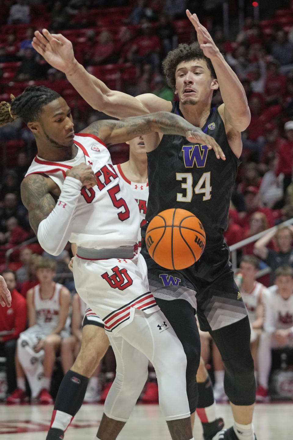 Utah guard Deivon Smith (5) and Washington center Braxton Meah (34) battle for a rebound during the first half of an NCAA college basketball game Sunday, Dec. 31, 2023, in Salt Lake City. (AP Photo/Rick Bowmer)