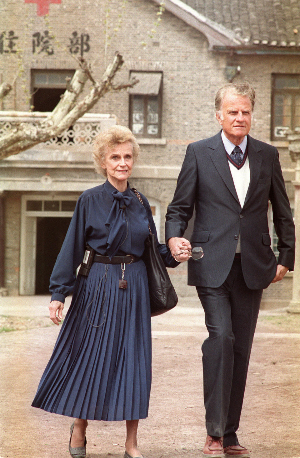 HUAIYIN, CHINA:  Billy Graham (R), the American evangelist and his wife Ruth walk 19 April 1988 in front of Ruth birthplace in Huaiyin, Jiangsu province, China. Graham, (son of a dairy farmer, born in 1918 in Charlotte, NC), attended Florida Bible Institute and was ordained a Southern Baptist minister in 1939 and quickly gained a reputation as a preacher. During the 1950s he conducted a series of highly organized revivalist campaigns in the USA and UK, and later in South America, the USSR and Western Europe. (Photo credit should read JOHN GIANNINI/AFP/Getty Images)