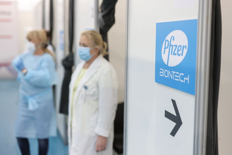 Healthcare workers wait in front of booths where people receive a dose of Pfizer's coronavirus disease (COVID-19) vaccine at Belgrade Fair vaccination center in Belgrade