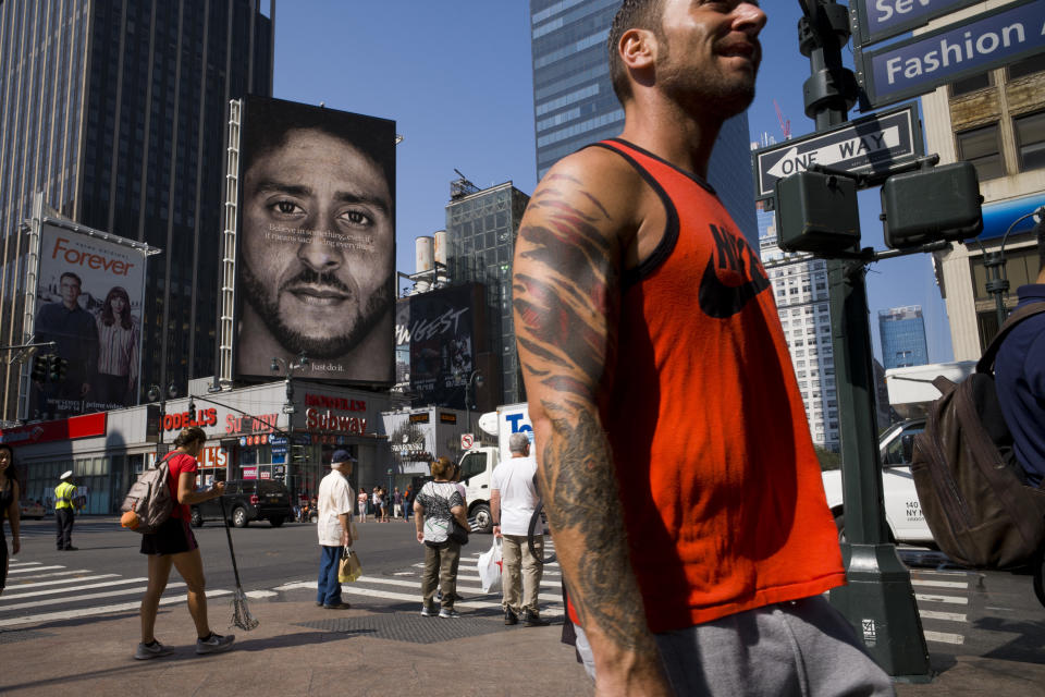 CORRECTS DATE- People walk by a Nike advertisement featuring Colin Kaepernick on display, Thursday, Sept. 6, 2018 in New York. Nike this week unveiled the deal with the former San Francisco 49ers quarterback, who's known for starting protests among NFL players over police brutality and racial inequality. (AP Photo/Mark Lennihan)