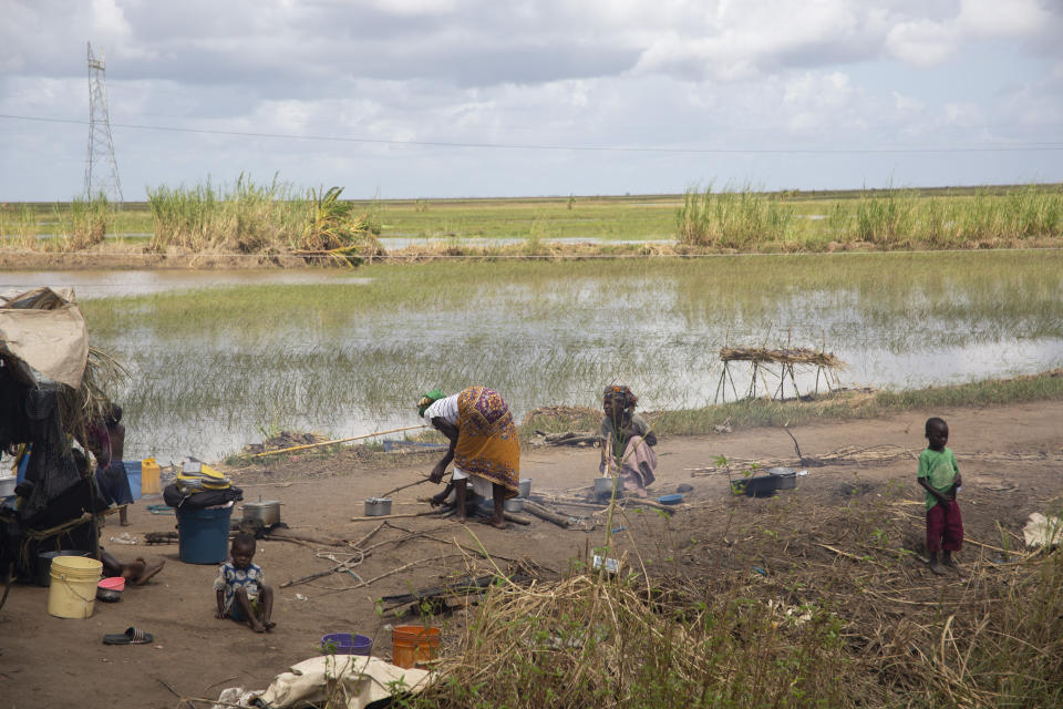 A mother prepares a meal for her family in a displacement camp on the bank of a flooded rice paddy near the village of Nicoadala, Zambezia province, Mozambique, Friday, March 24, 2023. Weeks after a massive cyclone hit Mozambique for a second time, the still-flooded country is facing a spiraling cholera outbreak which threatens to add to the devastation. (AP Photo/Tom Gould)