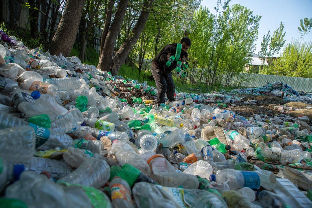 A waste worker in Srinagar, India sorts and collects plastic for recycling.