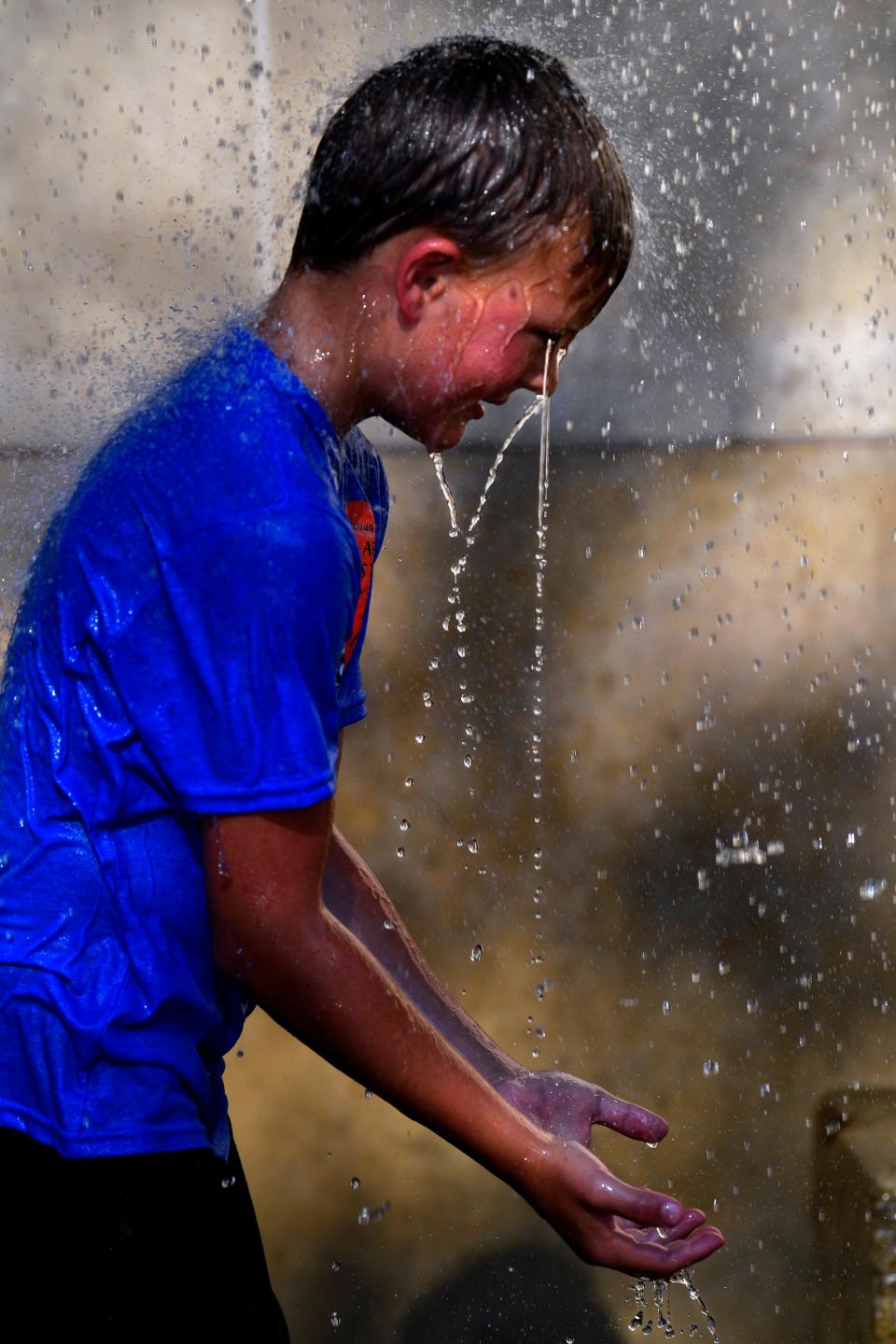Nolan Potts, 6, lets the waters from the Minter Park fountain run down his face after the Children's Art and Literacy Festival parade June 9. The temperature was only 99 degrees that day.