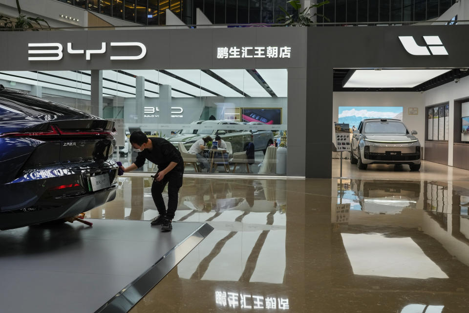 A worker wipes a Rising F7 car model at a floor section selling various Chinese-made electric car brands inside a shopping mall in Beijing, Tuesday, April 4, 2023. Furious at U.S. efforts that cut off access to technology to make advanced computer chips, China's leaders appear to be struggling to figure out how to retaliate without hurting their own ambitions in telecoms, artificial intelligence and other industries. (AP Photo/Andy Wong)