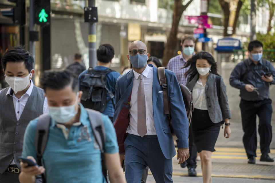 Workers cross the street in Hong Kong, Wednesday, Oct. 19, 2022. Hong Kong's leader on Wednesday unveiled a new visa scheme to woo global talent, as the city seeks to stem a brain drain that has risked its status as an international financial center. (AP Photo/Vernon Yuen)