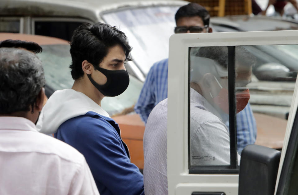Bollywood actor Shah Rukh Khan's son Aryan Khan, center, escorted by law enforcement officials from Narcotics Control Bureau office is being taken for a medical check up, in Mumbai, India, Friday, Oct. 08, 2021.(AP Photo/Rajanish kakade)