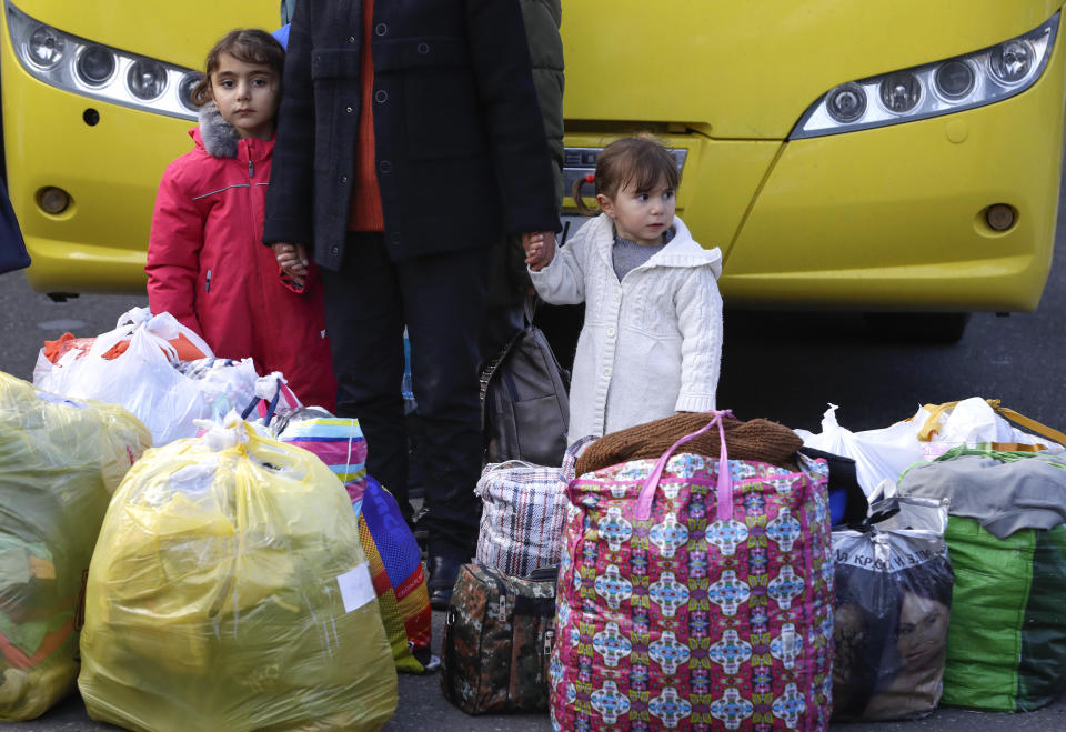 Ethnic Armenians refugee stand at their bags as they return to Stepanakert, the capital of the separatist region of Nagorno-Karabakh, on Tuesday, Nov. 17, 2020. Russian peacekeepers have started to move into the region, a total of 1,960 of them are to be sent in under a five-year mandate. Russia's Defense Ministry reported that the peacekeepers accompanied about 1,200 people returning to Nagorno-Karabakh from Armenia since Saturday. (AP Photo/Sergei Grits)