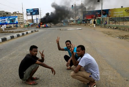 Sudanese protesters gesture as they sit-in near a barricade on a street, demanding that the country's Transitional Military Council handover power to civilians, in Khartoum