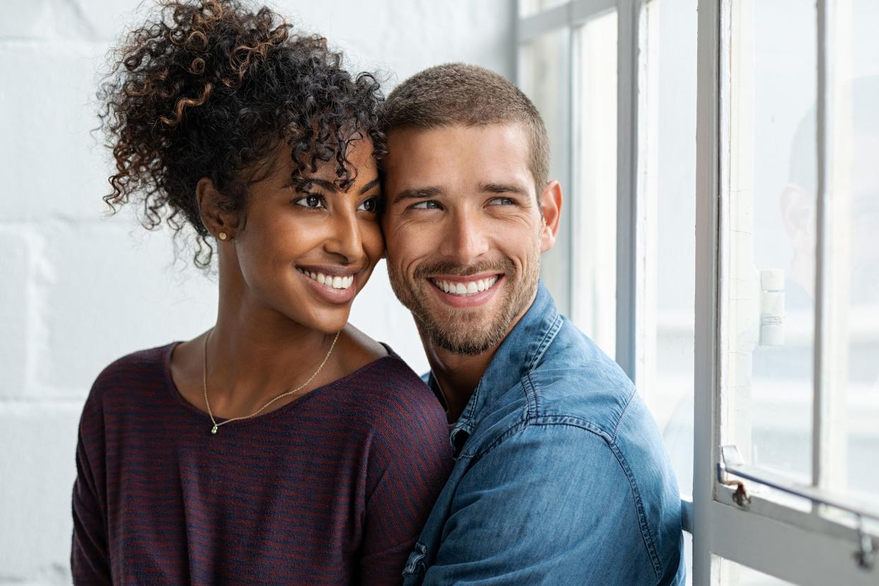 loving multiethnic couple embracing and sitting near window