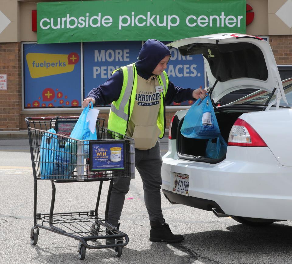 A Giant Eagle employee loads plastic-bagged groceries into the trunk of a customer's car.