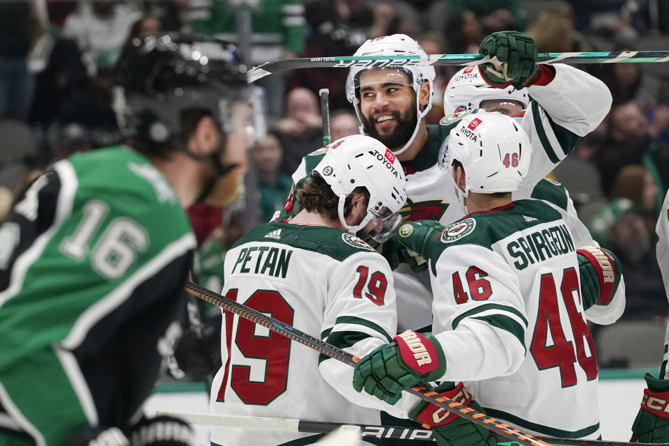 Minnesota Wild left wing Jordan Greenway (18) celebrates his goal with teammates Nic Petan (19) and Jared Spurgeon (46) as Dallas Stars center Joe Pavelski (16) skates past during the second period of an NHL hockey game in Dallas, Sunday, Dec. 4, 2022. (AP Photo/LM Otero)