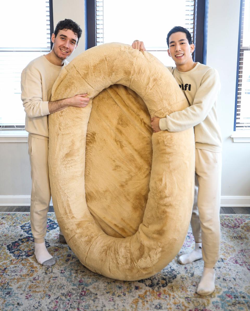 Noah Silverman and Yuki Kinoshita with one of the founders of Plufl, shows the human-sized dog bed can be used. The pair have been featured on Shark Tank for their idea. December 2022