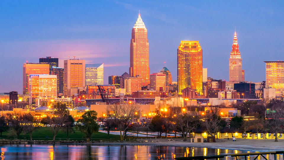 Downtown Cleveland, Ohio, glows in setting sunlight as the full moon prepares to rise under the pink clouds at center left.