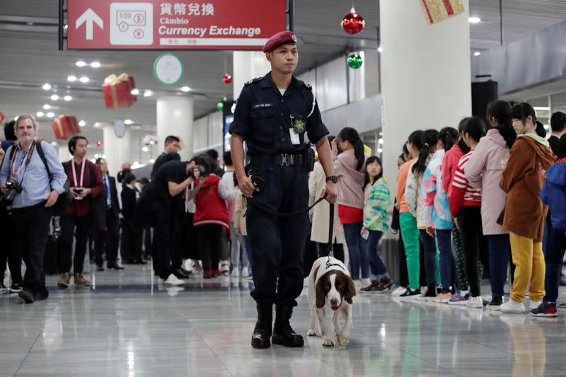 Security personnel walks with a sniffer dog before Chinese President Xi Jinping's arrival at Macau International Airport in Macau