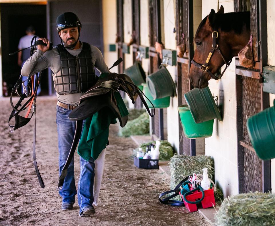 Exercise Rider Ronaldo Rodas carries his gear to his next ride while working at the Mayberry Farm's Ocala Breeders' Sales training barn Tuesday morning, May 10, 2022. Rich Strike was broken by rider Eddie Ordonez at Mayberry Farm in Ocala and trained by April Mayberry. The horse was an 80-1 longshot who made it into the Derby after a last-minute scratch on Friday. He was trained by Eric Reed and is owned by Rick Dawson. Jockey Sonny Leon led the horse to victory by passing Epicenter and Zandon in the last seconds of the race this past Saturday at Churchill Downs in Louisville, KY. during the 148th running of the Kentucky Derby.  [Doug Engle/Ocala Star Banner]2022