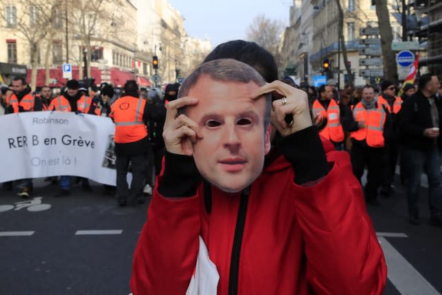 A protester holds a mask of French President Emmanuel Macron during a demonstration in Paris