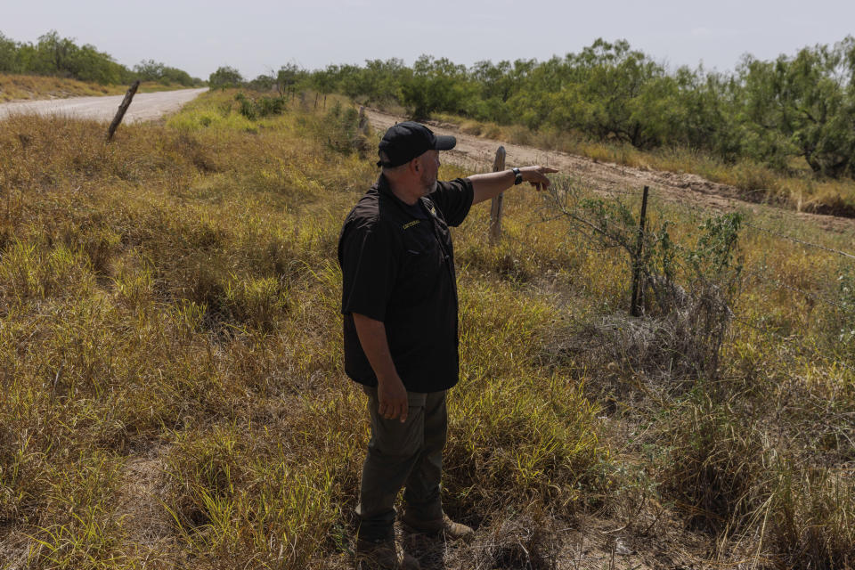 Jim Hogg County Sheriff's Investigator Ruben Garza investigates the location of a missing water station for immigrants containing sealed jugs of fresh water along a fence line near a roadway in rural Jim Hogg County, Texas, Tuesday, July 25, 2023. The South Texas Human Rights Center maintains over 100 blue barrels consistently stocked with water across rural South Texas to serve as a life-saving measure for immigrants who have crossed into the United States to travel north in the sweltering heat. (AP Photo/Michael Gonzalez)