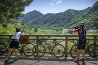 Yang Lan, right, takes a photo at a rest stop during group ride through the Baihe River Canyon in the northern outskirts of Beijing, Wednesday, July 13, 2022. Cycling has gained increasing popularity in China as a sport. A coronavirus outbreak that shut down indoor sports facilities in Beijing earlier this year encouraged people to try outdoor sports including cycling, which was only a major tool of transport before 2000. (AP Photo/Mark Schiefelbein)