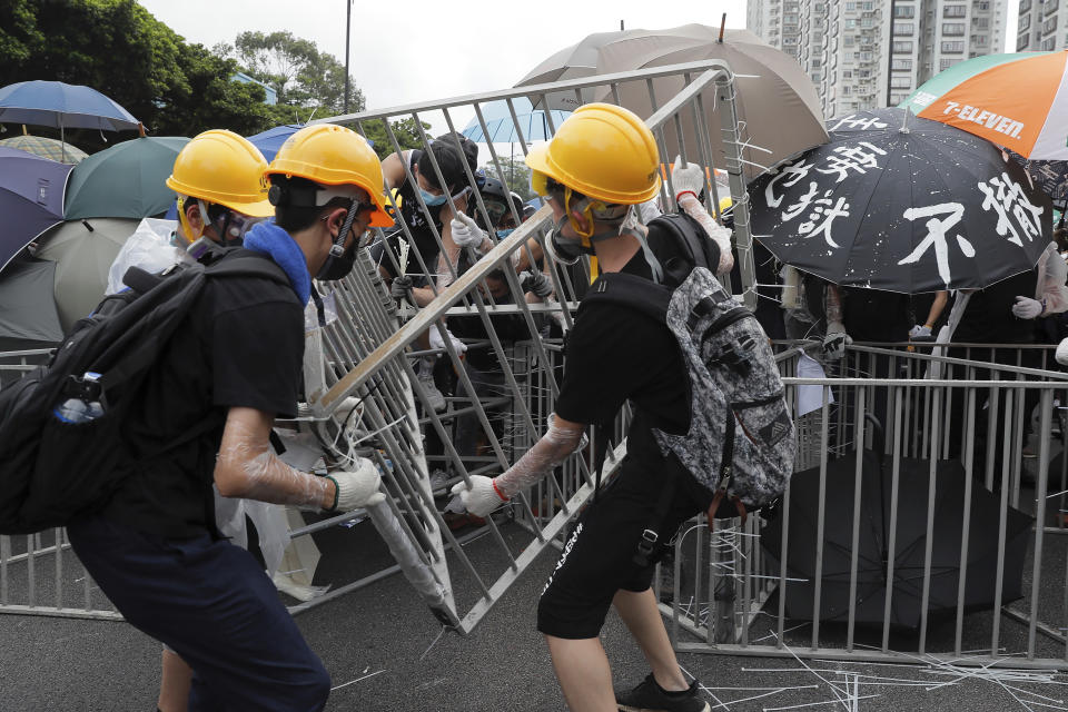 Protesters with umbrellas use steel barricades to block a road as they march through Sha Tin District in Hong Kong, Sunday, July 14, 2019. Opponents of a proposed Hong Kong extradition law have begun a protest march, adding to an outpouring of complaints the territory's pro-Beijing government is eroding its freedoms and autonomy. (AP Photo/Kin Cheung)
