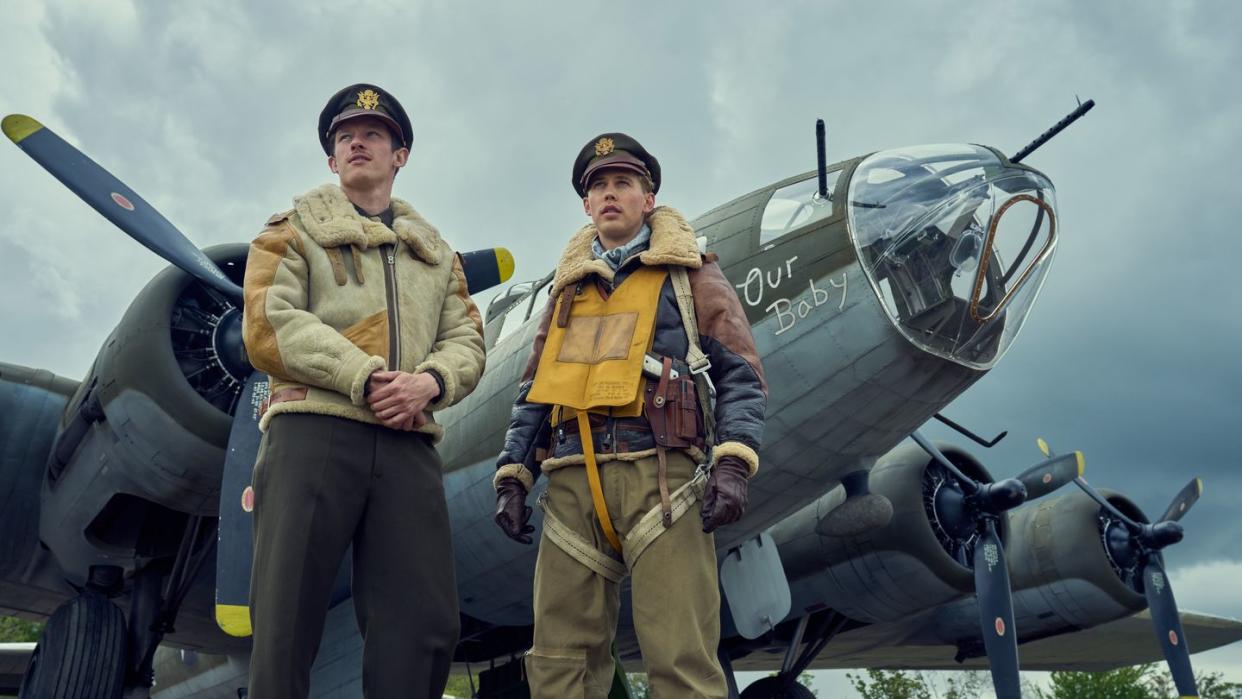 callum turner and austin butler star looking up and off camera while standing in front of bomber planes in a scene from masters of the air