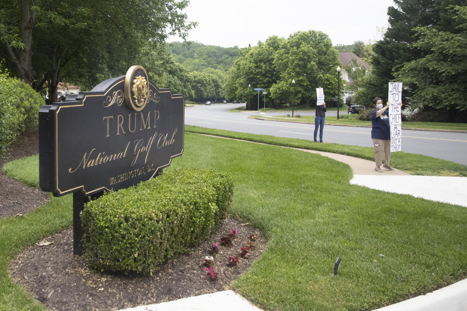 USA, Sterling: Aktivisten stehen mit Mundschutz am Trump National Golf Club in Sterling und halten Schilder in der Hand. Nach langer Pause wegen der Corona-Pandemie ist US-Präsident Trump am Wochenende wieder golfen gegangen - inmitten der Bemühungen, das Land wieder zu etwas Normalität zurückzubringen. Foto: Alex Brandon / AP / dpa