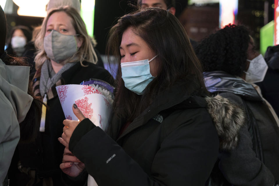 A person cries while holding a candle during a vigil in honor of Michelle Alyssa Go, a victim of a subway attack several days earlier, Tuesday, Jan. 18, 2022, in New York's Times Square. (AP Photo/Yuki Iwamura)