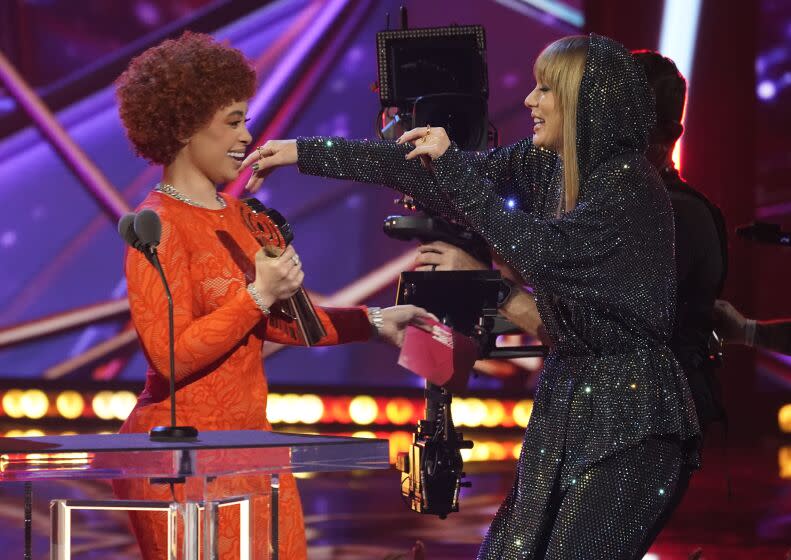 Ice Spice, left, presents an award to Taylor Swift