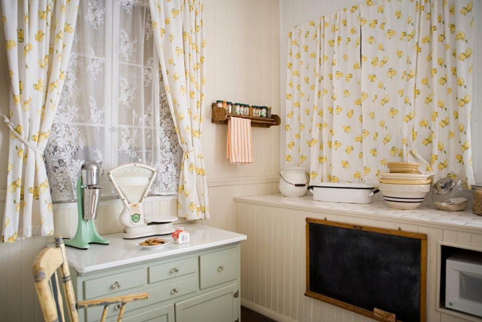 A small cottage kitchen with yellow curtains.