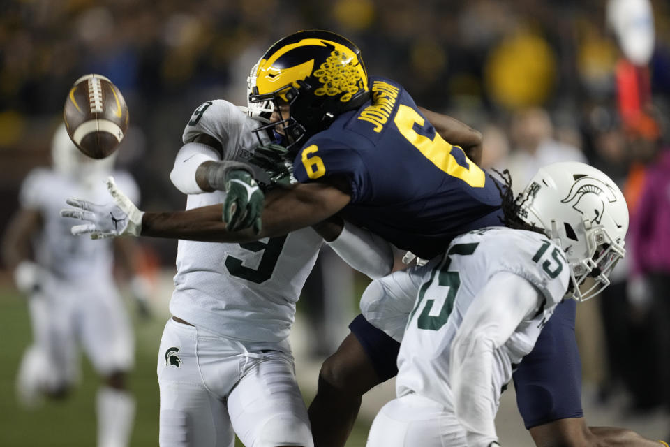 Michigan wide receiver Cornelius Johnson (6) tries to reach the ball while being defended by Michigan State cornerback Ronald Williams (9) and safety Angelo Grose (15) in the second half of an NCAA college football game in Ann Arbor, Mich., Saturday, Oct. 29, 2022. Pass interference was called on the play. (AP Photo/Paul Sancya)