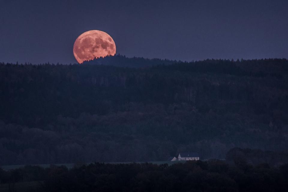 <p>A full moon tucks behind the Koenigshainer Berge mountains in Koenigshain, Germany // November 03, 2017</p>