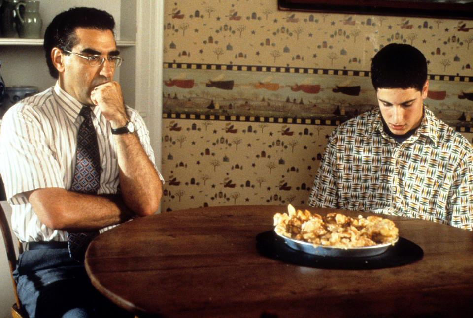 Eugene Levy and Jason Biggs sit at a table with a pie in the film "American Pie."