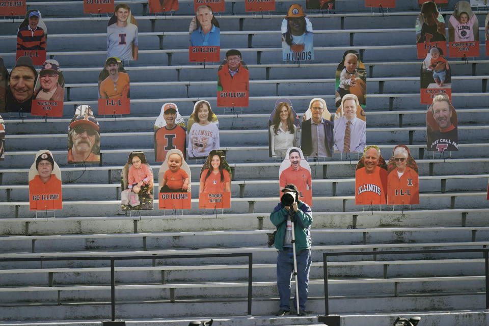 A photographer shoots pregame warmups near cardboard cutouts of fans before an NCAA college football game between Illinois and Purdue Saturday, Oct. 31, 2020, in Champaign, Ill. (AP Photo/Charles Rex Arbogast)