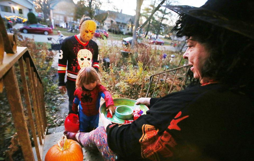 Lisa Fontaine hands out candies to Juan Perez and Adrian Perez (2) during trick or treating on Hodge Avenue on Monday, Oct. 31, in Ames, Iowa.
