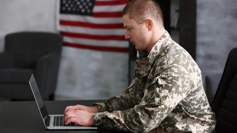 Soldier working with laptop in headquarters building.