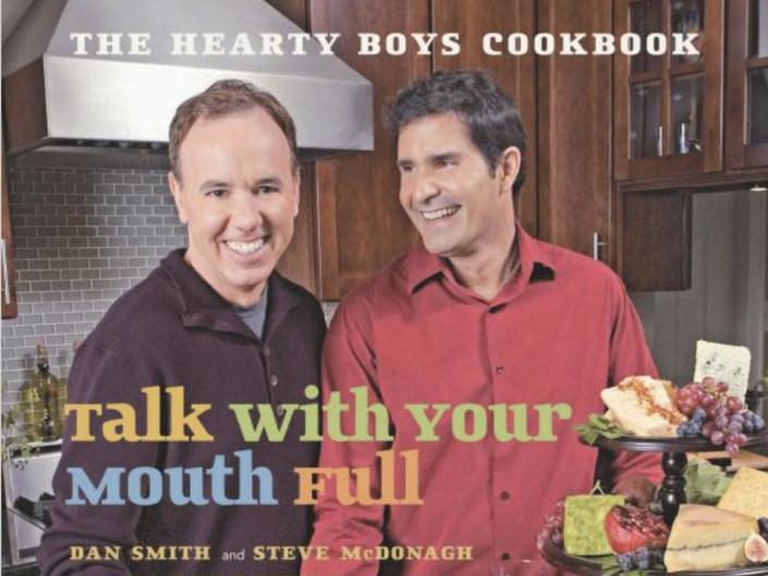 Dan and Steve smiling in a kitchen full of food with the printed words &quot;Eat With Your Mouth Full.&quot;