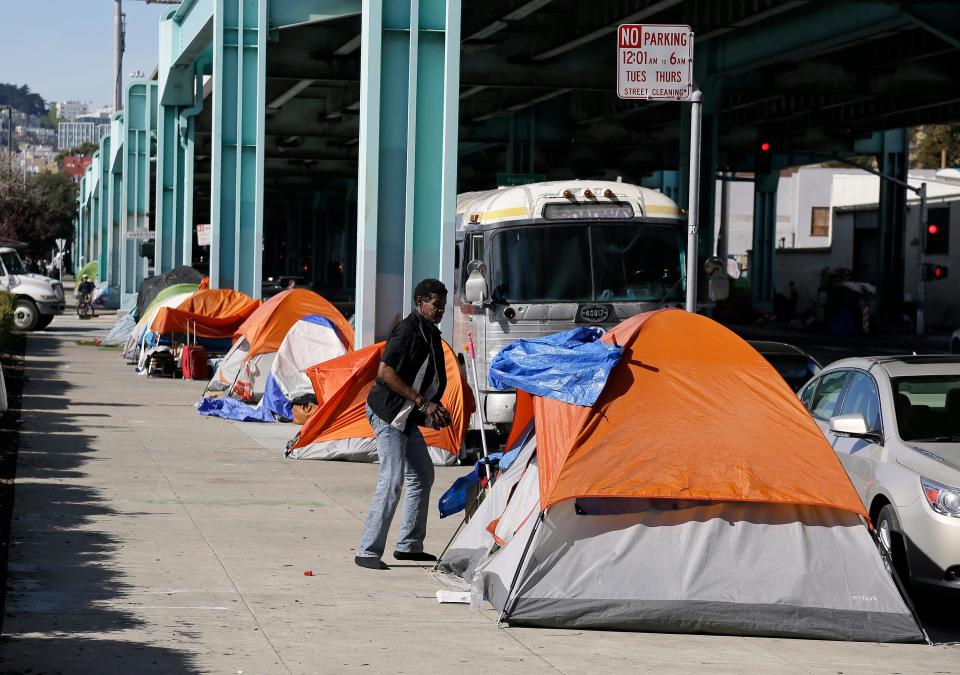 In this 2016 file photo, a man stands outside his tent on Division Street in San Francisco. California Gov. Gavin Newsom, outlined his plans in his proposed budget to spend $1.75 billion on housing in a state that is woefully short on units and $500 million on homelessness. In Newsom's first 100 days as governor, he's placed a moratorium on the death penalty, set aggressive goals to increase housing and battled with the Trump administration on immigration.