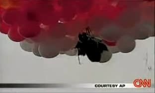 The priest in a seat contraption attached to hundreds of balloons up in the sky